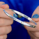 Sterling Silver Mia Hearts Bangle shown close up with model holding it. Hammered effect and brass hearts shown close up