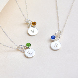 Birthstone and initial disc necklaces, various examples shown in close up shot.