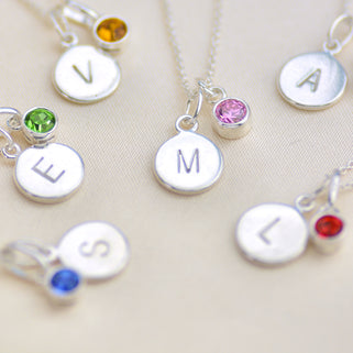 Birthstone and initial disc necklaces, various examples shown in close up shot.