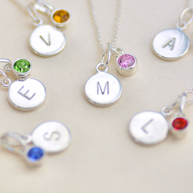 Birthstone and initial disc necklaces, various examples shown in close up shot.