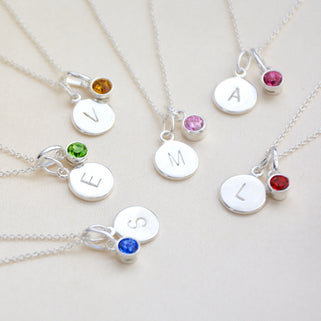 Birthstone and initial disc necklaces, various examples shown in close up shot.