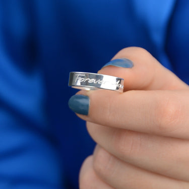 Personalised Unisex Silver Band Ring shown close up with model holding it and showing engraving on outside