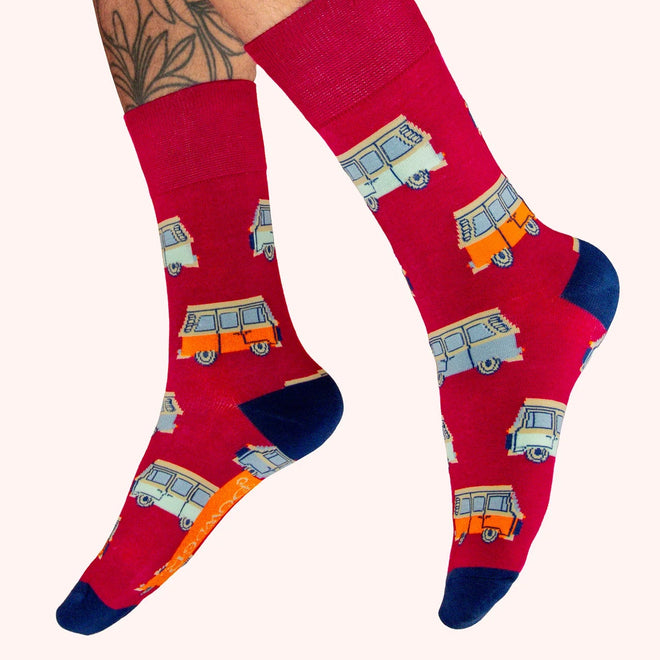 Red socks with camper van pattern worn by a person on a white background