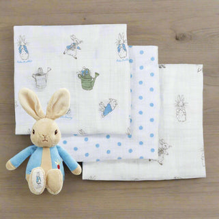 A set of three folded cotton muslin squares with embroidered animal patterns including a rabbit, a cat, and a mouse, accompanied by a soft plush toy resembling a rabbit, all with a Peter Rabbit theme.