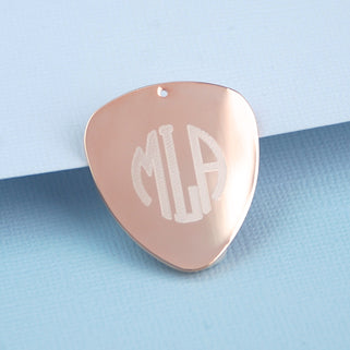 Rose gold guitar plectrums with personalised initials "MLA" engraved, shown in close up shot.