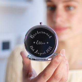 Bridesmaid Compact Mirror with "Ellie" engraved in the centre, "Bridesmaid" engraved at the top and "21st August 2021" engraved across the bottom shown in close up shot of model holding mirror