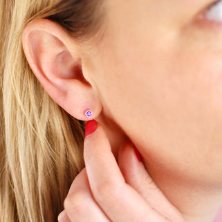 Tiny Sterling Silver February/Amethyst Birthstone Stud Earrings shown on close up of model