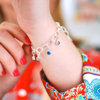 Personalised Family Birthstone Charm Bracelet - August/Peridot, June/Alexandrite, December/Blue Topaz, February/Amethyst, shown on model close up