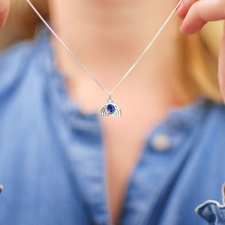 Necklace with silver rainbow charm and September/Sapphire birthstone shown in close up shot on model