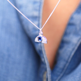 Necklace with silver rainbow charm and September/Sapphire birthstone shown in close up shot on model