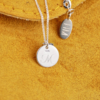 Back of Tree of Life Necklace with personalised "M" engraved and oval disc with "HM" shown in close up shot.