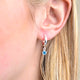 Sterling Silver Huggie Hoop Earrings with Blue Topaz/December birthstone charm, shown close up on model