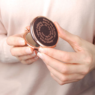 Rose gold compact mirror with personalised spiral message engraved on the front, shown in close up shot held by model