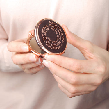 Rose gold compact mirror with personalised spiral message engraved on the front, shown in close up shot held by model