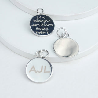 silver round bag charms with "Lou, Follow your heart, it knows the way. Sophie x" on the first charm, a plain blank charm on the second and "AJL" engraved on the third chime shown in a close up shot