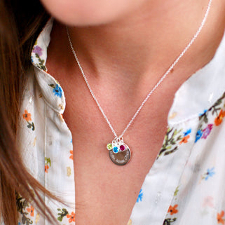 Personalised Family Names Birthstone Necklace - Silver engraved circle disc with "Bella, James, Olivia" and three birthstones  August/Peridot, December/Blue topaz,  July/Ruby shown on model