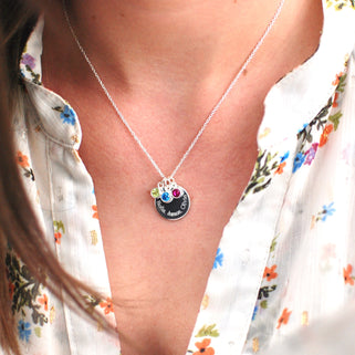 Personalised Family Names Birthstone Necklace - Silver engraved circle disc with "Bella, James, Olivia" and three birthstones  August/Peridot, December/Blue topaz,  July/Ruby shown on model