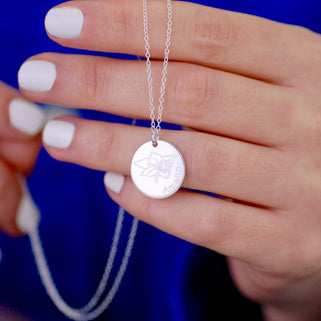 Silver circle disc necklace with March/Daffodil birth flower and "Amelia" engraved shown close up