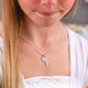 Girl's Sterling Silver Cross Necklace with S Initial Disc and August Peridot birth stone shown on model