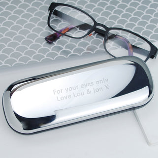 Chrome Glasses Case with Personalised Message "For your eyes only Love Lou & Jon X" engraved, shown in close up shot on desk with glasses 