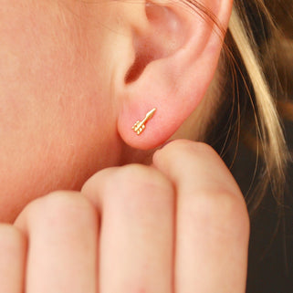 Tiny Gold Vermeil Arrow Stud Earrings shown in close up shot of model wearing them