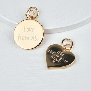 Gold Bag Disc Charms, circle charm on the left with "Love from Abi" and heart charm on the right with "Ella Follow your heart x" personalised engraved message