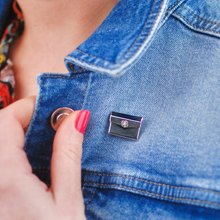 Lucky envelope pin with 4 leaf clover engraved on the front, shown on models denim jacket.