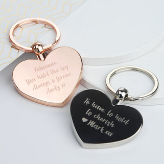 Rose gold and silver heart keyrings shown with personalised messages engraved in close up shot together.