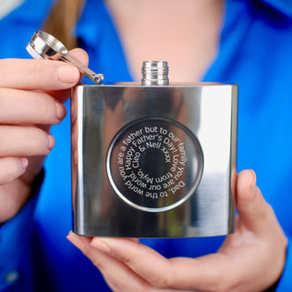 Silver hip flask with engraved spiral message on the front shown in close up shot with model.