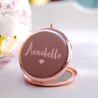 Rose gold compact mirror with personalised name "Annabelle" engraved with heart icon beneath, shown in close up shot
