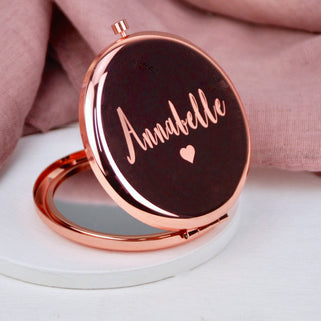 Rose gold compact mirror with personalised name "Annabelle" engraved with heart icon beneath, shown in close up shot
