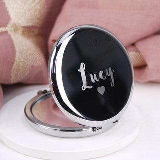 Silver compact mirror with personalised name "Lucy" engraved with heart icon beneath, shown in close up shot