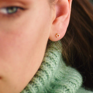 Gold vermeil tiny open star stud earrings shown in close up on model