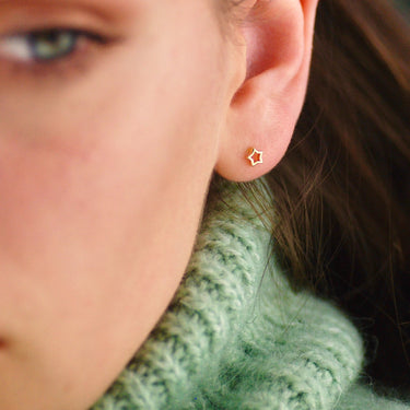 Gold vermeil tiny open star stud earrings shown in close up on model