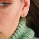 Gold vermeil tiny open star stud earrings shown in close up on model