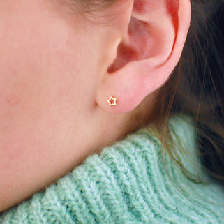 Gold vermeil tiny open star stud earrings shown in close up on model