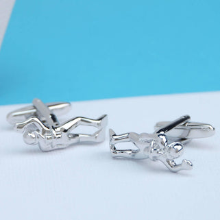 Silver divers cufflinks shown in close up shot on white and blue background