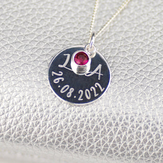 Sterling Silver Celebration Necklace. Silver round disc with "L&A 26.08.2022" engraved and October/Tourmaline birthstone, shown in close up shot