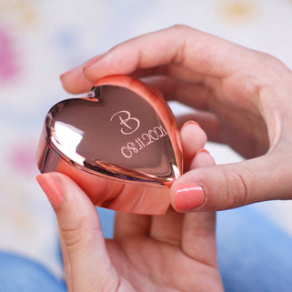 personalised rose gold plated heart trinket box with "B" in the centre and "08.11.2021" engraved underneath, shown in close up shot with model.