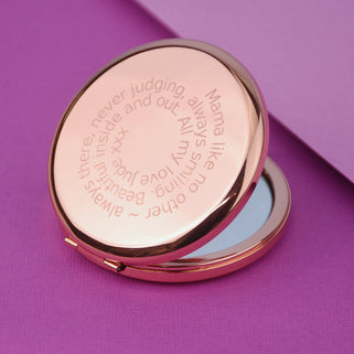 Rose gold compact mirror with personalised spiral message engraved on the front, shown in close up shot on purple background.