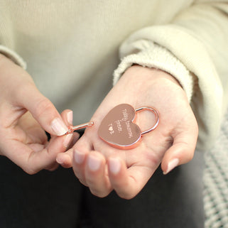 Rose gold lovers padlock and key with "Today, tomorrow, forever. T heart B" engraved on the front, shown in close up shot with model.