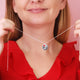 silver circle disc necklace with rose flower engraving and Ruby/July birthstone on satellite chain shown on close up of model