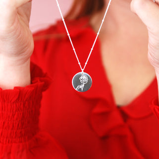 silver circle disc necklace with rose flower engraving on satellite chain shown on close up of model