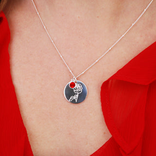 silver circle disc necklace with rose flower engraving and Ruby/July birthstone on satellite chain shown on close up of model
