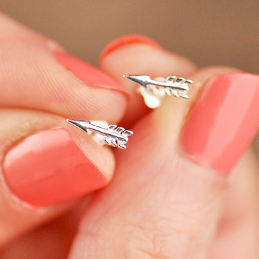 Sterling Silver Tiny Arrow Stud Earrings shown in close up shot held by model