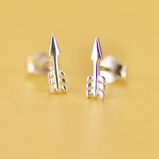 Pair of Sterling Silver Tiny Arrow Stud Earrings shown in close up shot on yellow background