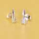 Pair of Sterling Silver Tiny Arrow Stud Earrings shown in close up shot on yellow background