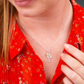 Silver cross charm necklace with August/Peridot birthstone charm, shown on close up shot of model