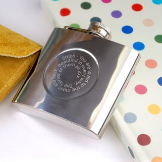 Silver hip flask with engraved spiral message on the front shown in close up shot.