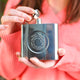 Silver hip flask with engraved spiral message on the front shown in close up shot with model.